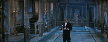 Movie still from “Three Coins in the Fountain” (1954), directed by Jean Negulesco – A man in a tuxedo holding a trophy in front of a building; Wide shot, High angle