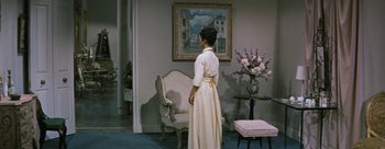 Movie still from “Three Coins in the Fountain” (1954), directed by Jean Negulesco – A woman standing in front of a painting in a living room; Wide shot, Low angle