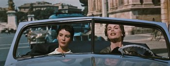 Movie still from “Three Coins in the Fountain” (1954), directed by Jean Negulesco – Two women sitting in the back seat of a car; Medium shot, Low angle