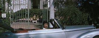 Movie still from “Three Coins in the Fountain” (1954), directed by Jean Negulesco – A man sitting in the driver's seat of an antique car; Wide shot, High angle