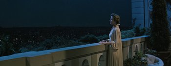 Movie still from “Three Coins in the Fountain” (1954), directed by Jean Negulesco – A woman standing on a balcony looking out at a city; Medium shot, Low angle