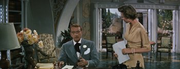 Movie still from “Three Coins in the Fountain” (1954), directed by Jean Negulesco – A man sitting at a table in a suit and tie next to a woman; Medium shot, Over the shoulder angle