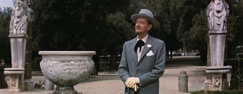 Movie still from “Three Coins in the Fountain” (1954), directed by Jean Negulesco – An older man wearing a suit and tie and a hat; Medium shot, Low angle