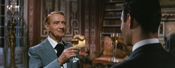 Movie still from “Three Coins in the Fountain” (1954), directed by Jean Negulesco – A man holding a wine glass in his right hand; Medium shot, Over the shoulder angle