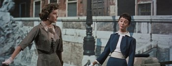 Movie still from “Three Coins in the Fountain” (1954), directed by Jean Negulesco – Two women standing next to each other in front of a building; Medium shot, Low angle