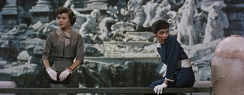Movie still from “Three Coins in the Fountain” (1954), directed by Jean Negulesco – Two people sitting in front of a wall with a painting behind them; Medium shot, Over the shoulder angle
