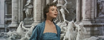 Movie still from “Three Coins in the Fountain” (1954), directed by Jean Negulesco – A woman in a blue dress standing in front of a painting; Close Up shot, Low angle