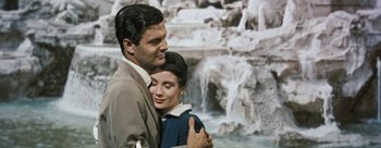 Movie still from “Three Coins in the Fountain” (1954), directed by Jean Negulesco – A man and a woman hugging in front of a waterfall; Medium shot, High angle