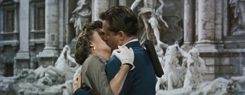Movie still from “Three Coins in the Fountain” (1954), directed by Jean Negulesco – A man and a woman kissing in front of a statue; Medium shot, High angle