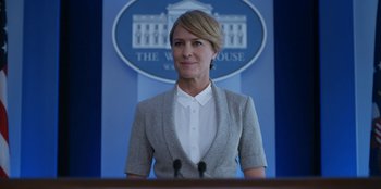 Movie still from “House of Cards” (2013), created by Beau Willimon – A woman standing in front of a podium in front of the white house; Medium shot, Low angle