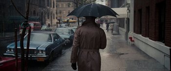 Movie still from “Three Days of the Condor” (1975), directed by Sydney Pollack – A man walking down a street holding an umbrella; Wide shot, Over the shoulder angle