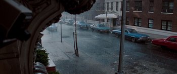 Movie still from “Three Days of the Condor” (1975), directed by Sydney Pollack – A rainy street scene with cars parked on the side of the road; Extreme Wide shot, High angle