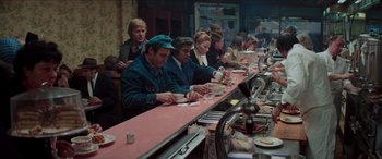 Movie still from “Three Days of the Condor” (1975), directed by Sydney Pollack – A group of people sitting at a long bar; Wide shot, High angle