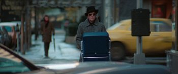 Movie still from “Three Days of the Condor” (1975), directed by Sydney Pollack – A man in a hat and sunglasses is walking down the street; Wide shot, Over the shoulder angle