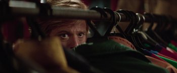 Movie still from “Three Days of the Condor” (1975), directed by Sydney Pollack – A person looking through clothes hangers; Close Up shot, Over the shoulder angle