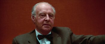 Movie still from “Three Days of the Condor” (1975), directed by Sydney Pollack – An older man wearing a suit and a bow tie; Close Up shot, Low angle