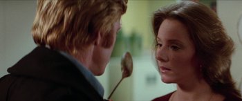 Movie still from “Three Days of the Condor” (1975), directed by Sydney Pollack – A man and a woman holding a wooden spoon in a room; Close Up shot, Over the shoulder angle