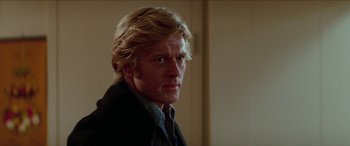 Movie still from “Three Days of the Condor” (1975), directed by Sydney Pollack – A person wearing a suit and tie; Close Up shot, Over the shoulder angle