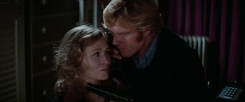 Movie still from “Three Days of the Condor” (1975), directed by Sydney Pollack – A man and a woman holding a gun in a dark room; Close Up shot, Low angle