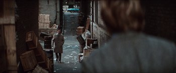 Movie still from “Three Days of the Condor” (1975), directed by Sydney Pollack – A man walking down a street with a bunch of trash; Wide shot, Over the shoulder angle