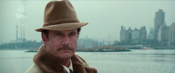 Movie still from “Three Days of the Condor” (1975), directed by Sydney Pollack – A person wearing a hat near a body of water; Close Up shot, Over the shoulder angle
