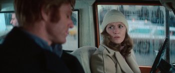 Movie still from “Three Days of the Condor” (1975), directed by Sydney Pollack – A woman sitting next to a man in a car; Close Up shot, Over the shoulder angle