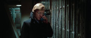 Movie still from “Three Days of the Condor” (1975), directed by Sydney Pollack – A man talking on a phone while wearing glasses; Close Up shot, Low angle