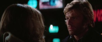 Movie still from “Three Days of the Condor” (1975), directed by Sydney Pollack – A man and a woman talking in front of a television; Close Up shot, Over the shoulder angle