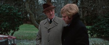 Movie still from “Three Days of the Condor” (1975), directed by Sydney Pollack – A man wearing a hat and a coat talking to another man wearing a hat; Close Up shot, Over the shoulder angle