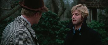 Movie still from “Three Days of the Condor” (1975), directed by Sydney Pollack – Two men are standing in a forest talking; Close Up shot, Over the shoulder angle
