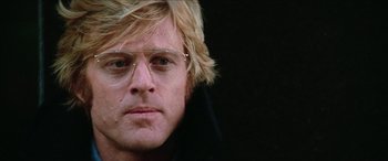 Movie still from “Three Days of the Condor” (1975), directed by Sydney Pollack – A person wearing glasses and a jacket; Close Up shot, Low angle