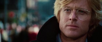 Movie still from “Three Days of the Condor” (1975), directed by Sydney Pollack – A man with blonde hair wearing glasses and a black jacket; Close Up shot, Low angle