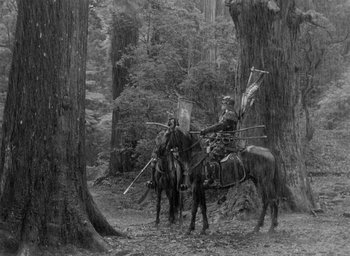 Movie still from “Throne of Blood” (1957), directed by Akira Kurosawa – A man on a horse is riding through the woods; Wide shot, High angle