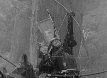 Movie still from “Throne of Blood” (1957), directed by Akira Kurosawa – A man holding a bow and arrow while standing in the rain; Medium shot, Low angle