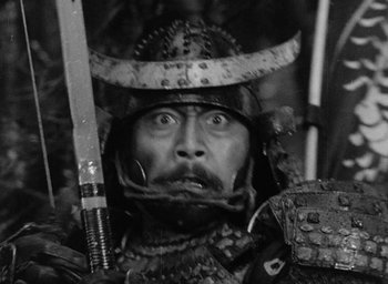 Movie still from “Throne of Blood” (1957), directed by Akira Kurosawa – A person holding a sword and wearing a helmet; Close Up shot, Low angle