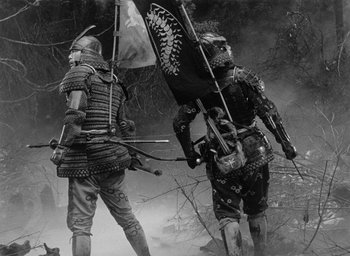 Movie still from “Throne of Blood” (1957), directed by Akira Kurosawa – Two men in samurai garb are holding a flag; Wide shot, Low angle