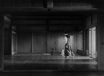 Movie still from “Throne of Blood” (1957), directed by Akira Kurosawa – A man walking in a room with a broom in front of him; Extreme Wide shot, Low angle
