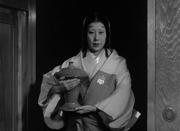 Movie still from “Throne of Blood” (1957), directed by Akira Kurosawa – A woman in a kimono holding a bowl; Medium shot, Low angle