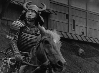 Movie still from “Throne of Blood” (1957), directed by Akira Kurosawa – A man wearing a horned helmet riding a horse; Medium shot, Low angle