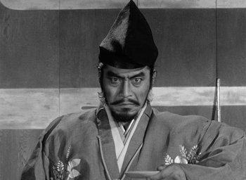 Movie still from “Throne of Blood” (1957), directed by Akira Kurosawa – An old photo of an asian man in a hat; Medium shot, Low angle