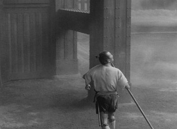 Movie still from “Throne of Blood” (1957), directed by Akira Kurosawa – A man is walking in the rain with a pole; Wide shot, High angle
