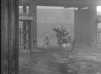Movie still from “Throne of Blood” (1957), directed by Akira Kurosawa – An old photo of a man riding a horse in a barn; Wide shot, High angle