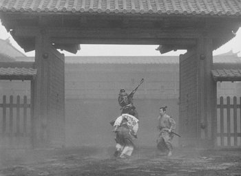 Movie still from “Throne of Blood” (1957), directed by Akira Kurosawa – A man riding a horse in the middle of a dirt field; Wide shot, Low angle