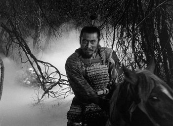 Movie still from “Throne of Blood” (1957), directed by Akira Kurosawa – A man standing next to a horse in a forest; Medium shot, Over the shoulder angle