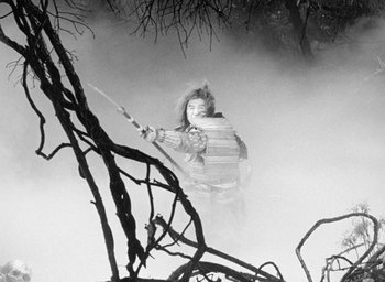 Movie still from “Throne of Blood” (1957), directed by Akira Kurosawa – A man in a costume holding a sword in a foggy forest; Wide shot, Low angle