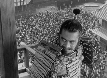Movie still from “Throne of Blood” (1957), directed by Akira Kurosawa – A man in a samurai suit standing in front of a crowd; Medium shot, High angle