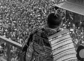 Movie still from “Throne of Blood” (1957), directed by Akira Kurosawa – A man in a crowd of people with a bird on his head; Extreme Wide shot, High angle