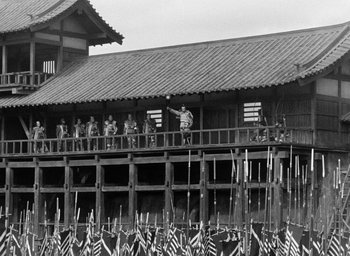 Movie still from “Throne of Blood” (1957), directed by Akira Kurosawa – A group of people standing on top of a wooden building; Extreme Wide shot, Low angle