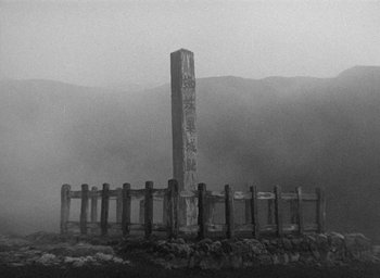 Movie still from “Throne of Blood” (1957), directed by Akira Kurosawa – A tall stone pillar surrounded by a wooden fence; Extreme Wide shot, Low angle