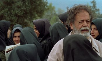 Movie still from “Through the Olive Trees” (1994), directed by Abbas Kiarostami – A group of people sitting on top of each other; Close Up shot, Over the shoulder angle